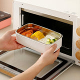 Hands placing the removable 304 stainless steel food tray into an oven for reheating meals.