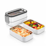 White 2-tier stainless steel bento box opened to show food compartments filled with noodles and fruit.