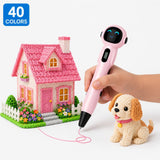 Pink cordless kids 3D pen with 40-colour PCL filament set — child drawing a fluffy puppy and pink cottage with garden