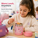 Girl at school desk eating warm pasta from a pink unicorn Misanbroo kids insulated food jar with a folding spoon at lunchtime