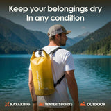 Man wearing yellow 15L Ocean Pack dry bag as a backpack near a mountain lake for hiking and camping.